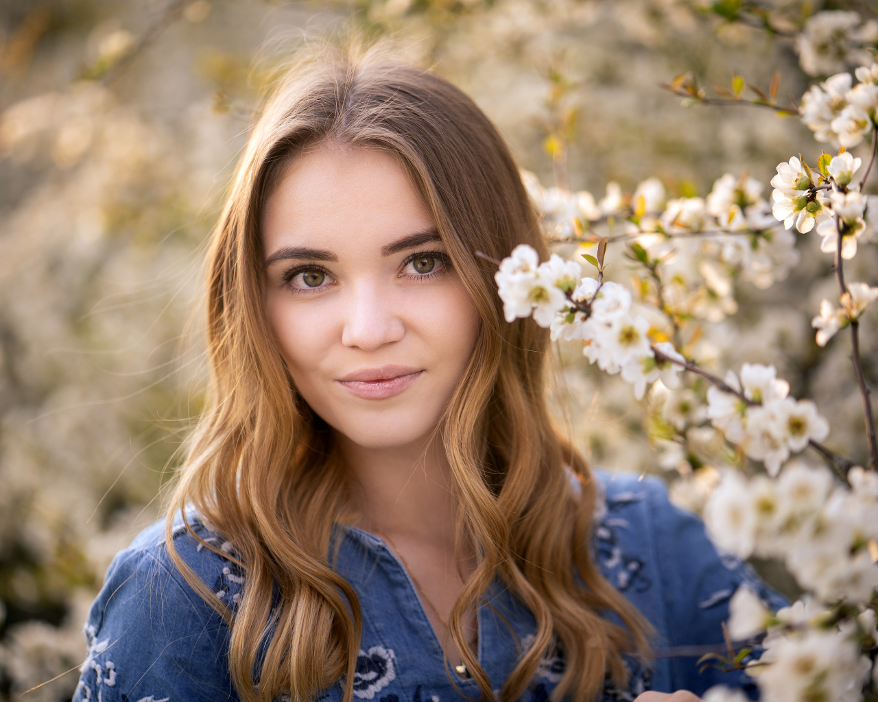 Красивая девушка у ветки с белыми цветами