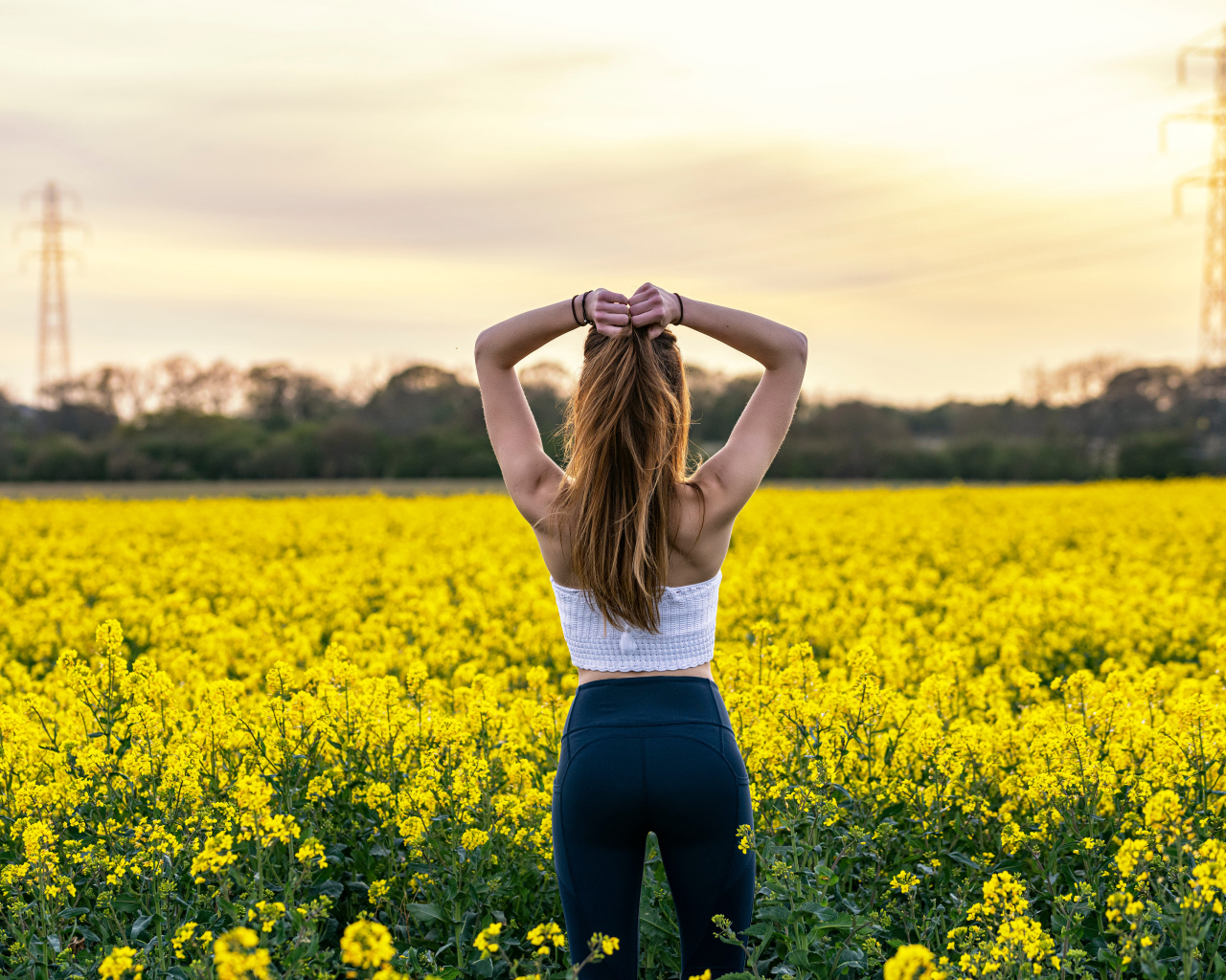 Красивая девушка стоит на поле с рапсом