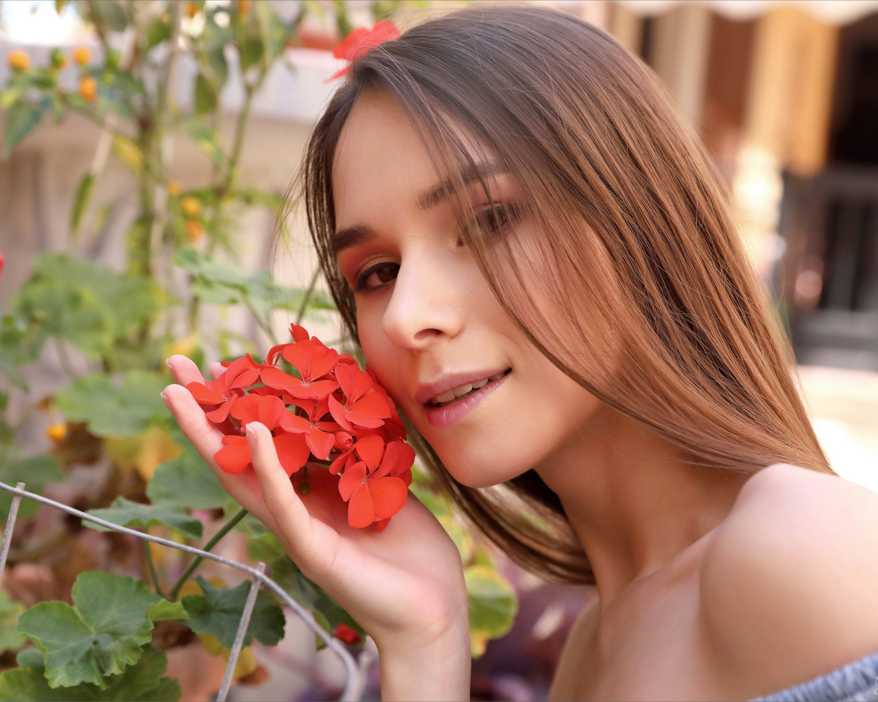 Красивая девушка с красным цветком герани 