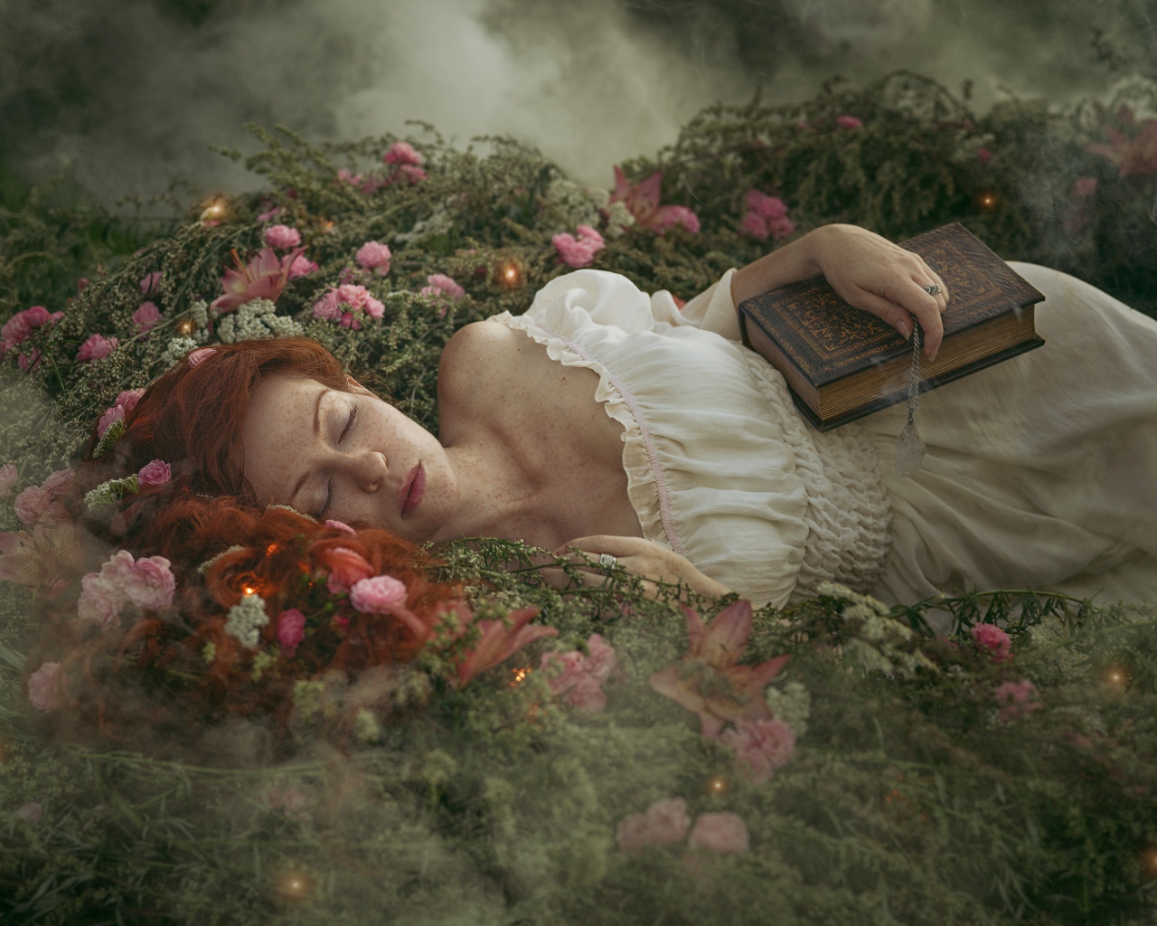 Красивая рыжеволосая девушка спит на земле с книгой