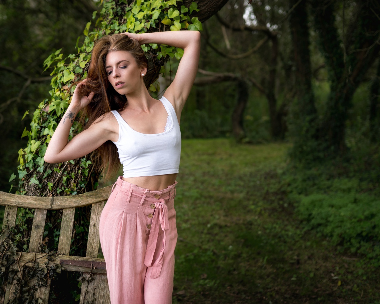 Красивая стройная девушка стоит у дерева 