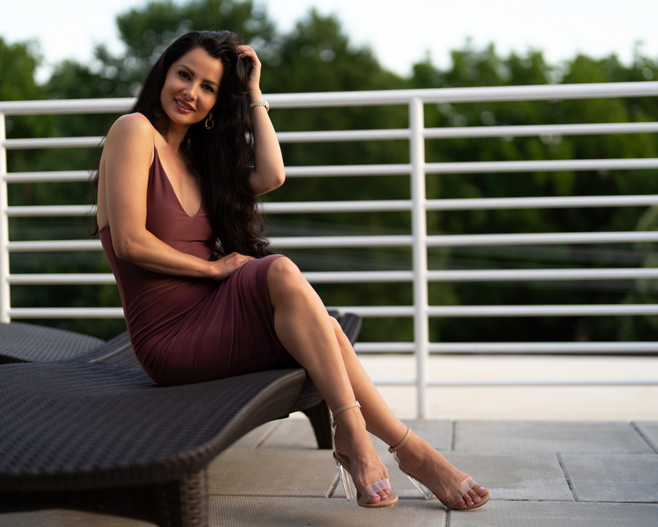 Красивая стильная брюнетка в платье сидит на диване