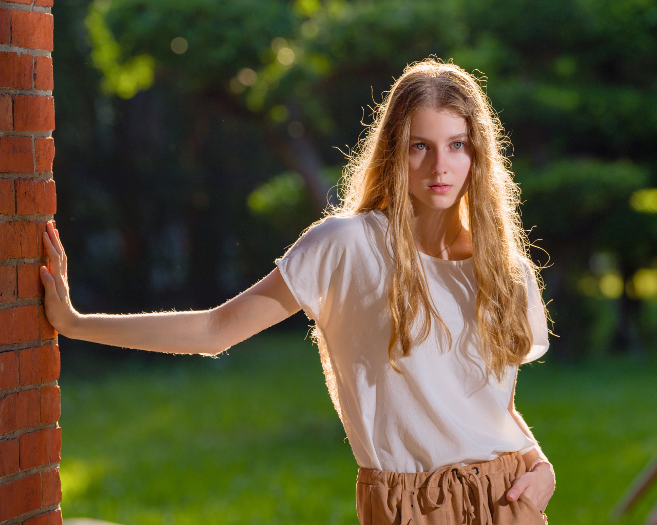 Красивая нежная девушка стоит у стены 