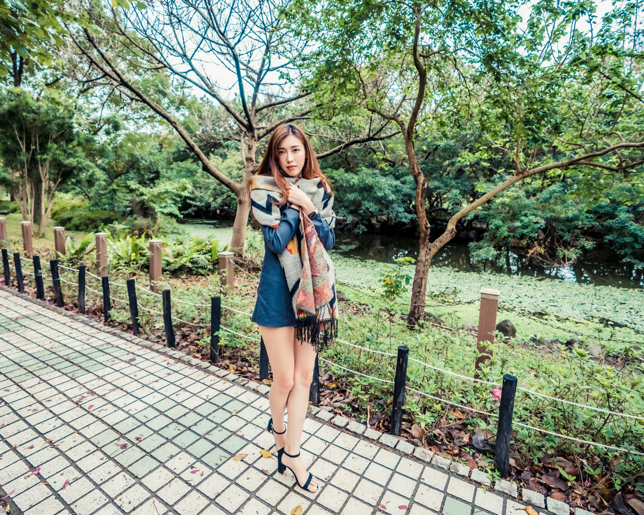 Милая девушка азиатка стоит в осеннем парке 