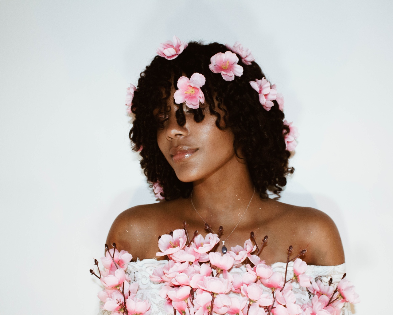Темнокожая девушка в розовых цветах на сером фоне