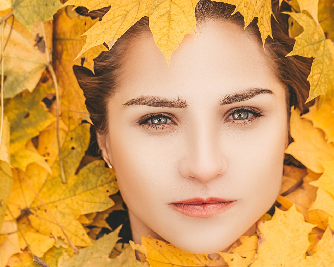 Лицо красивой молодой девушки в желтой листве