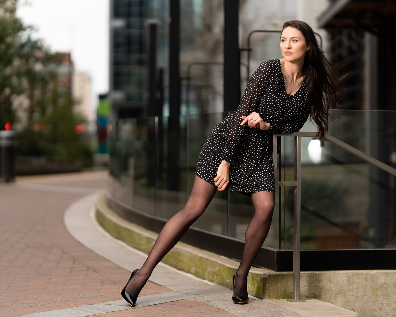 Девушка в черном платье в горошек у здания