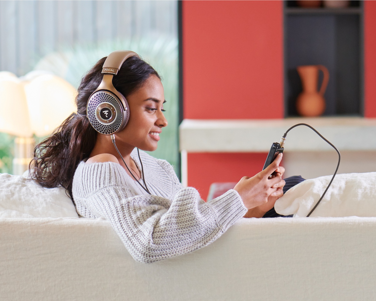 Девушка модель в наушниках на диване с плеером