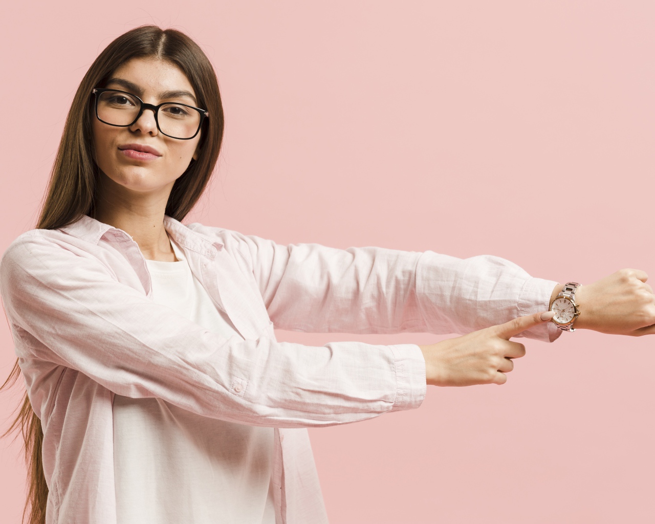 Девушка с часами на руке на розовом фоне 