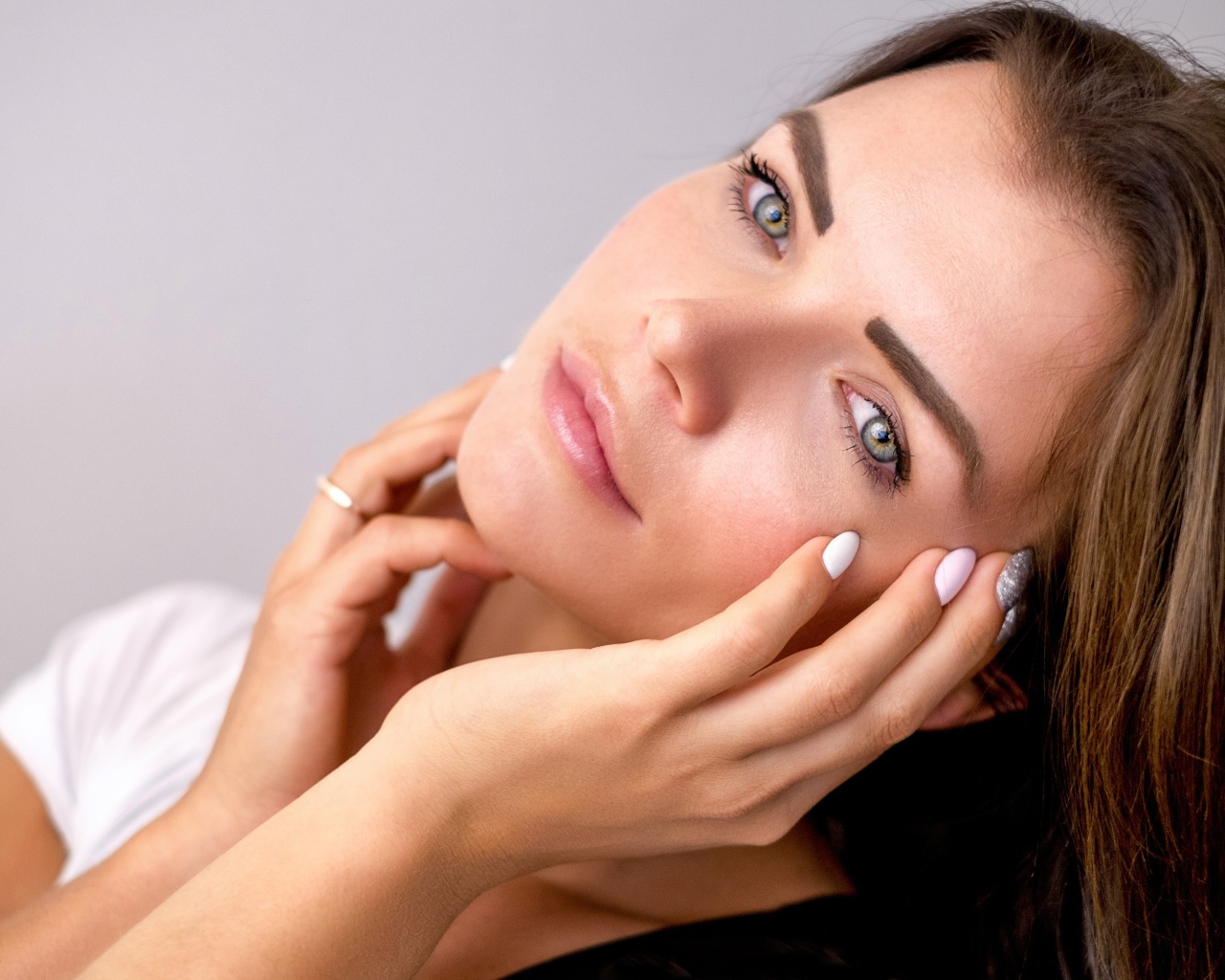 Девушка с руками у лица на сером фоне