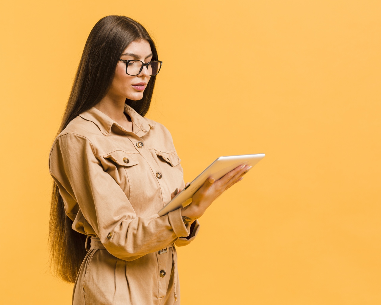 Девушка с планшетов руках на желтом фоне