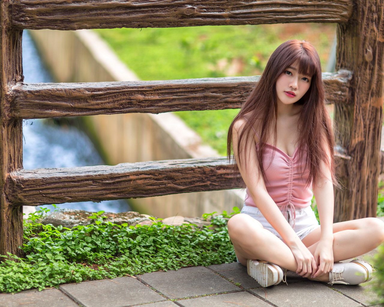 Длинноволосая азиатка сидит у забора 