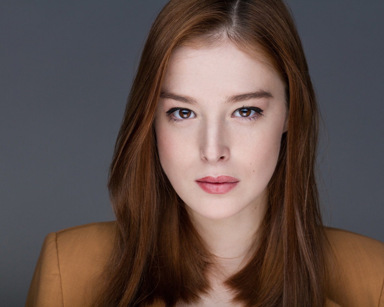 Рыжеволосая  молодая девушка на сером фоне