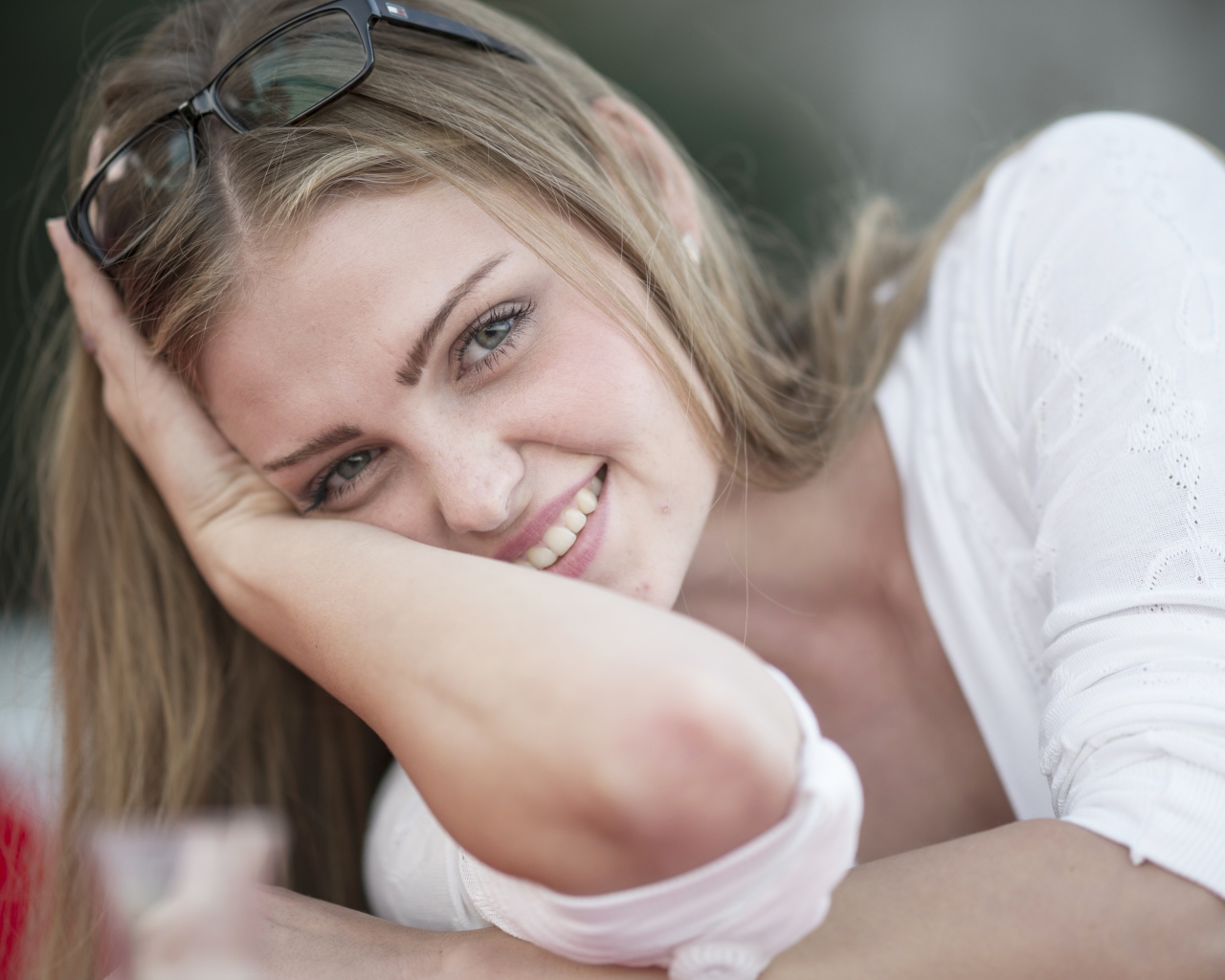 Улыбающаяся девушка блондинка с очками на голове