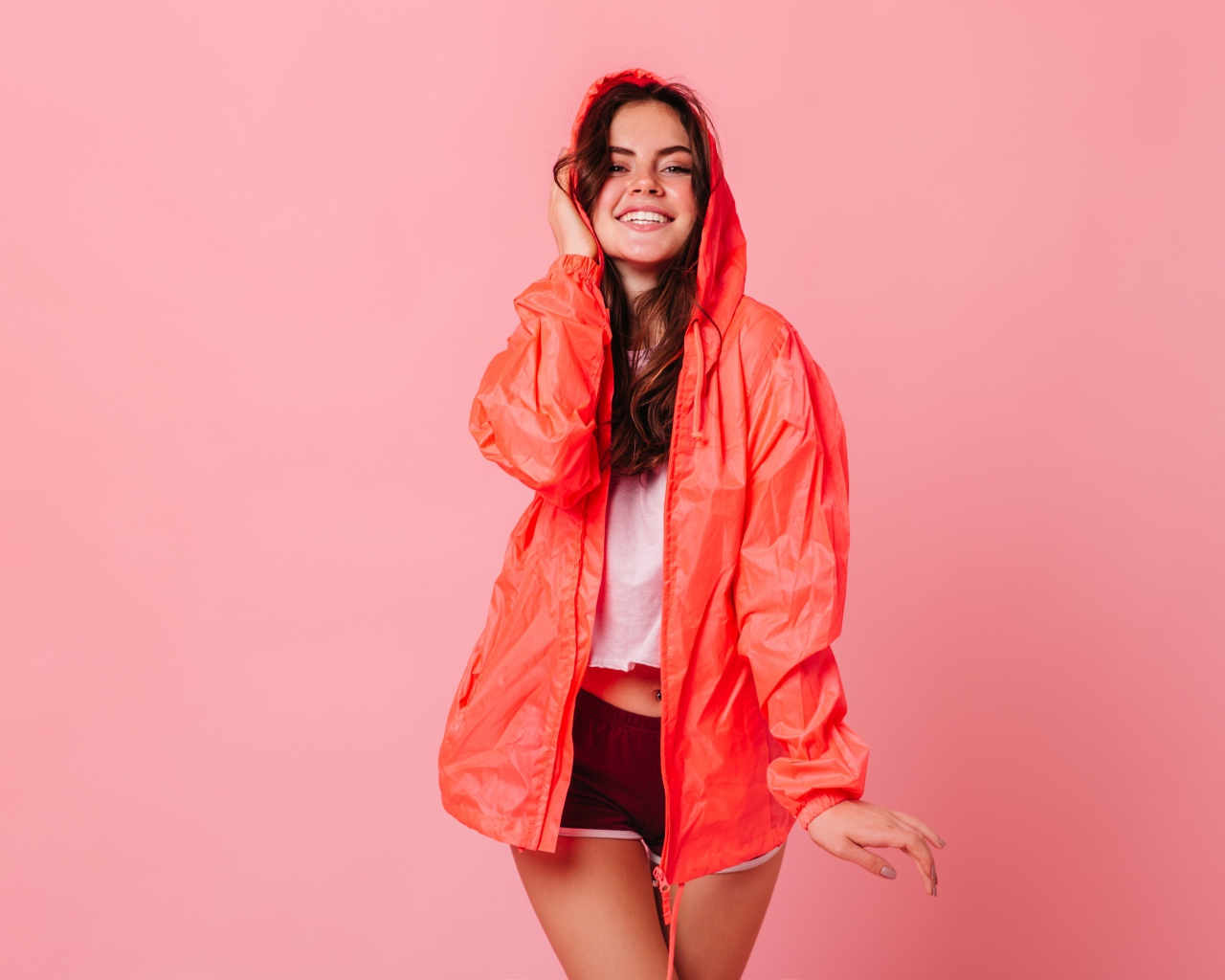 Улыбающаяся девушка в плаще на розовом фоне