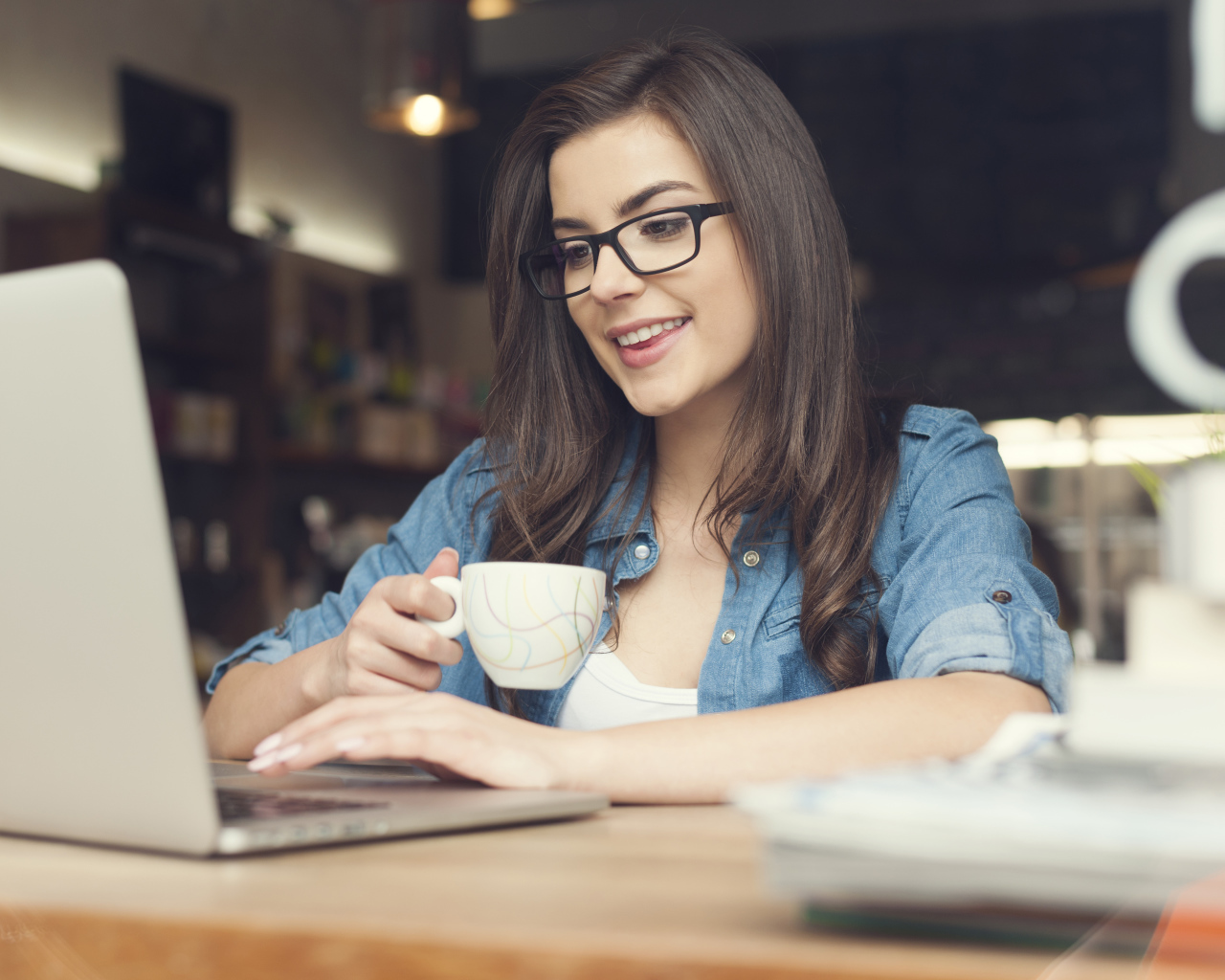 Улыбающаяся девушка в очках с ноутбуком