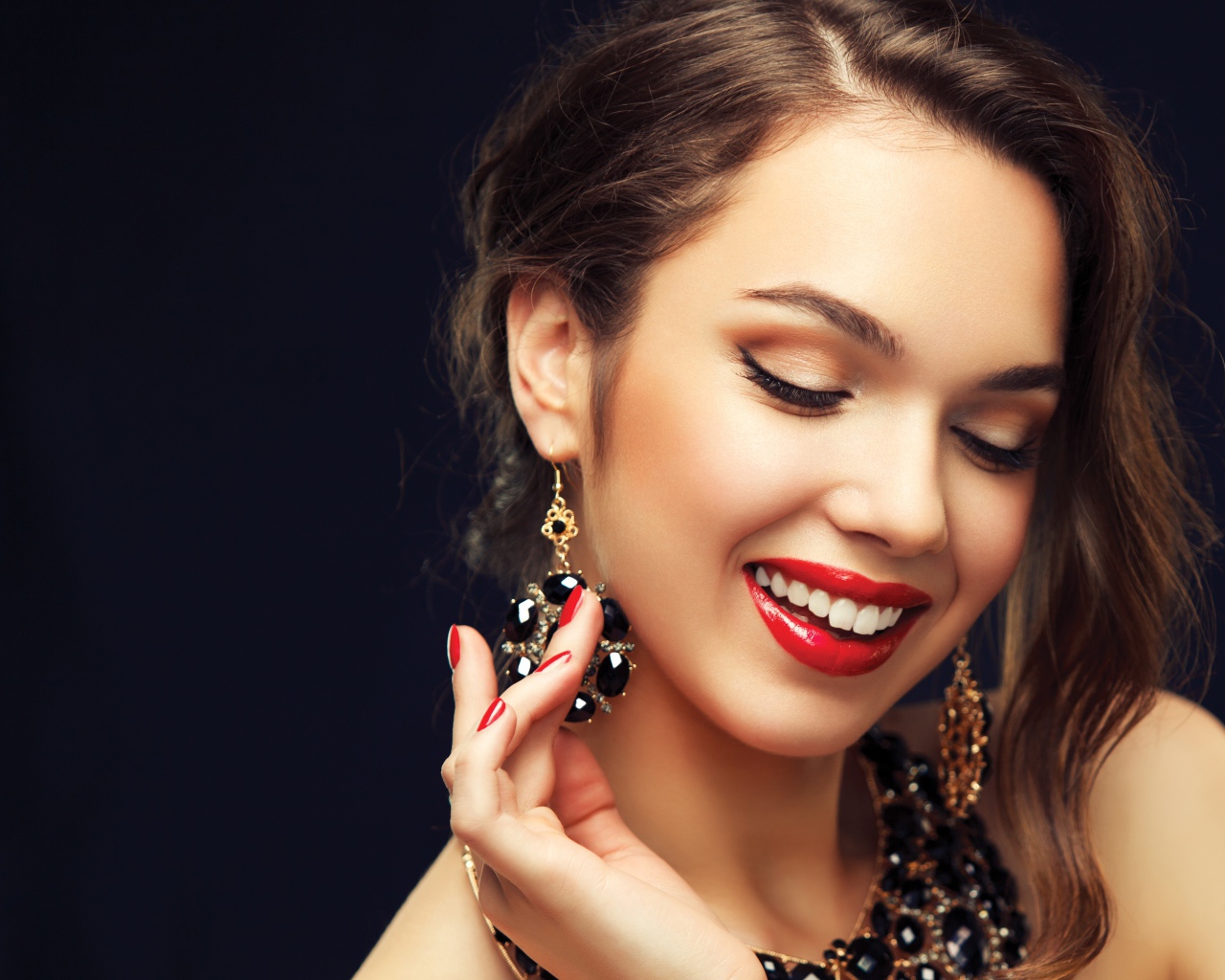 Улыбающаяся девушка носит украшения с черными камнями