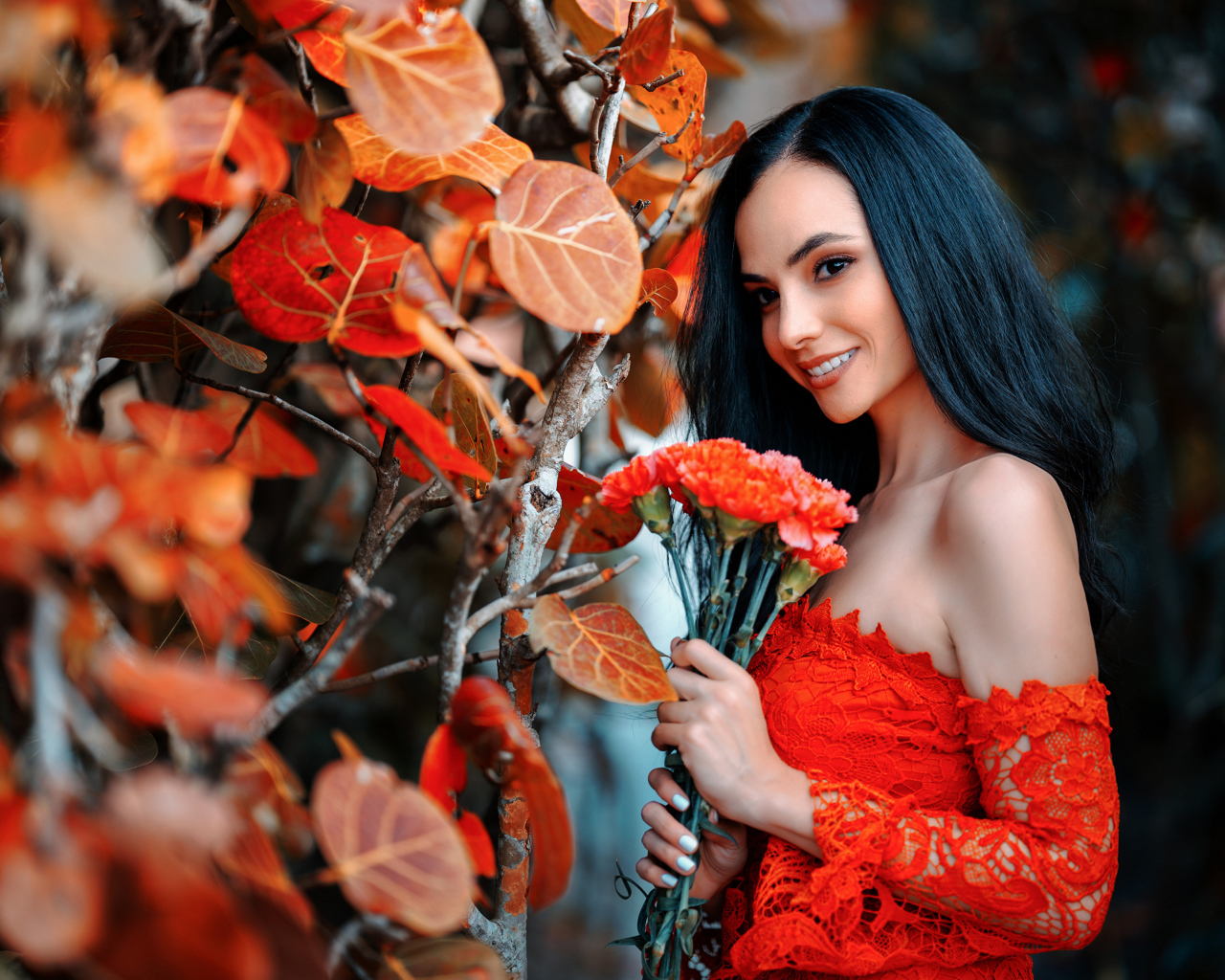 Улыбающаяся девушка с букетом гвоздик у стены с осенними листьями