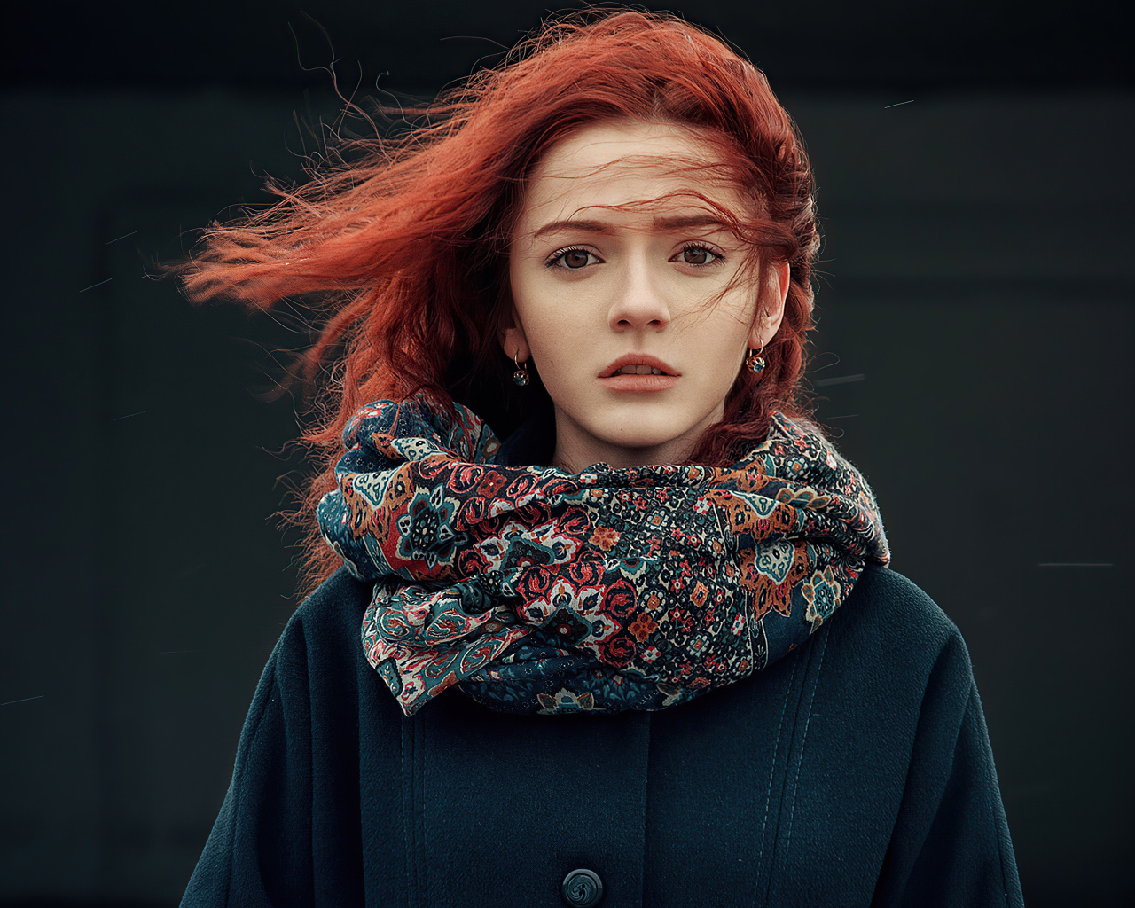 Ветер развивает волосы рыжеволосой девушки в пальто