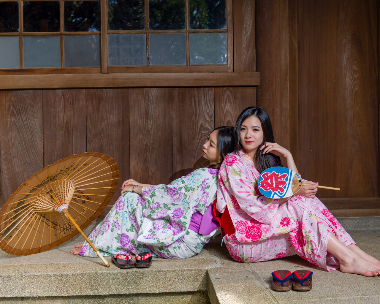 Две молодые девушки в кимоно сидят на полу