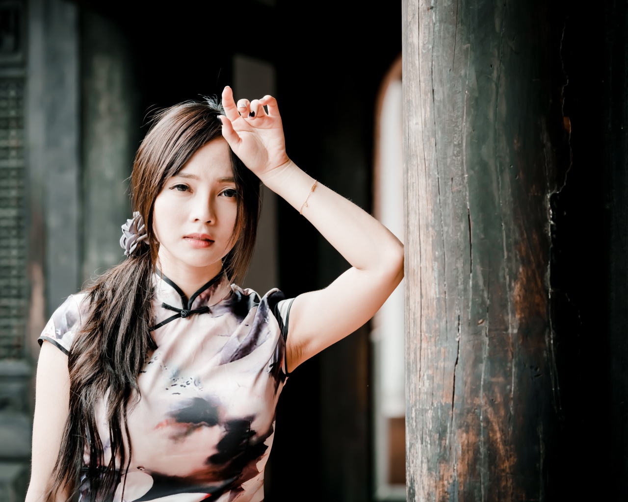 Молодая девушка азиатка стоит у столба 