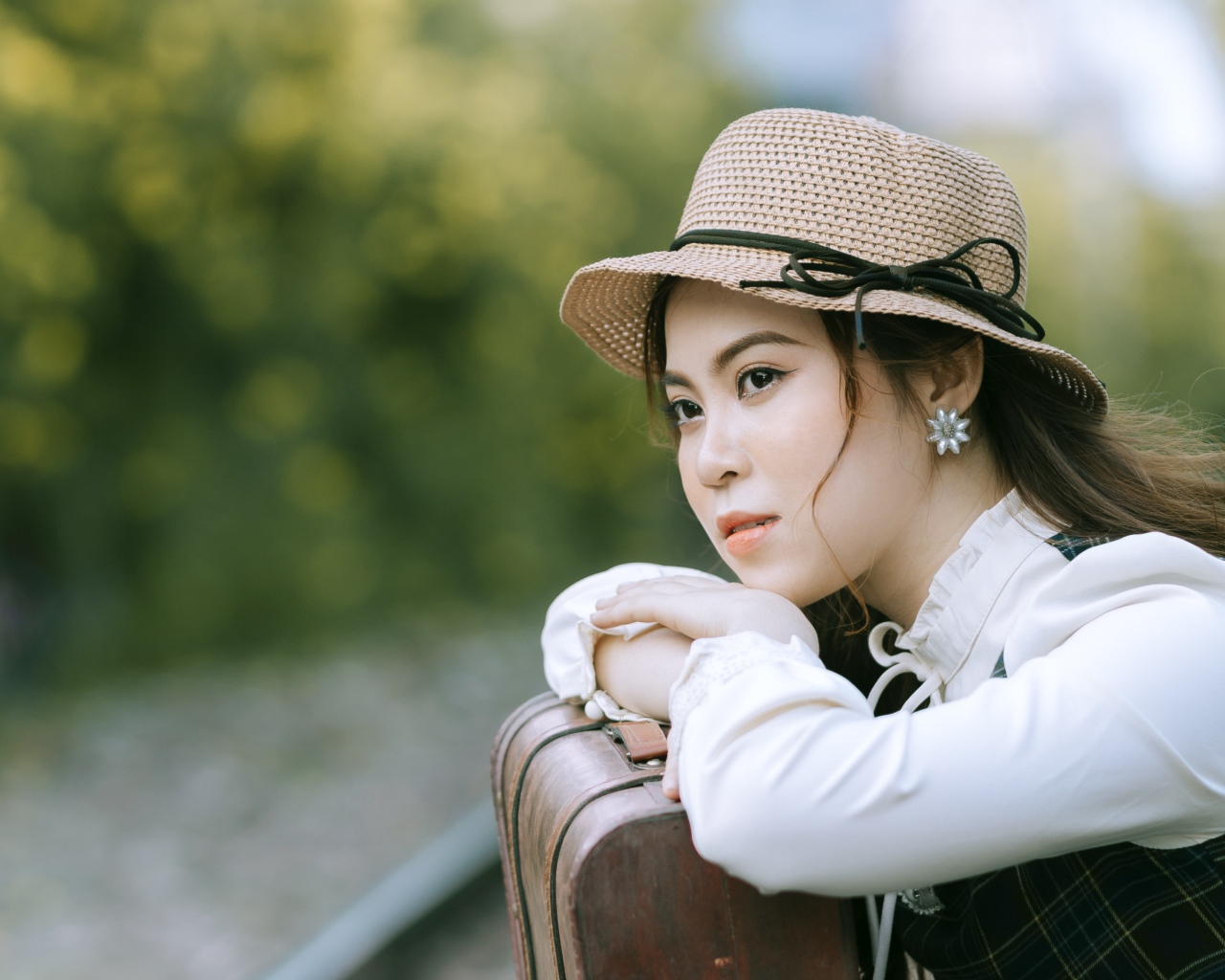 Молодая азиатка в шляпе с чемоданом