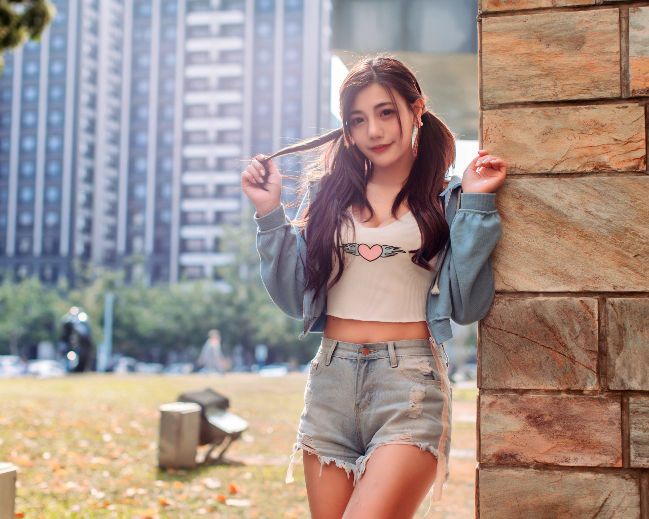 Молодая азиатка в коротких шортах стоит у стены