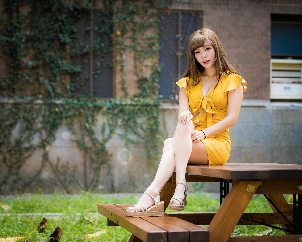 Молодая азиатка сидит в парке на столе 