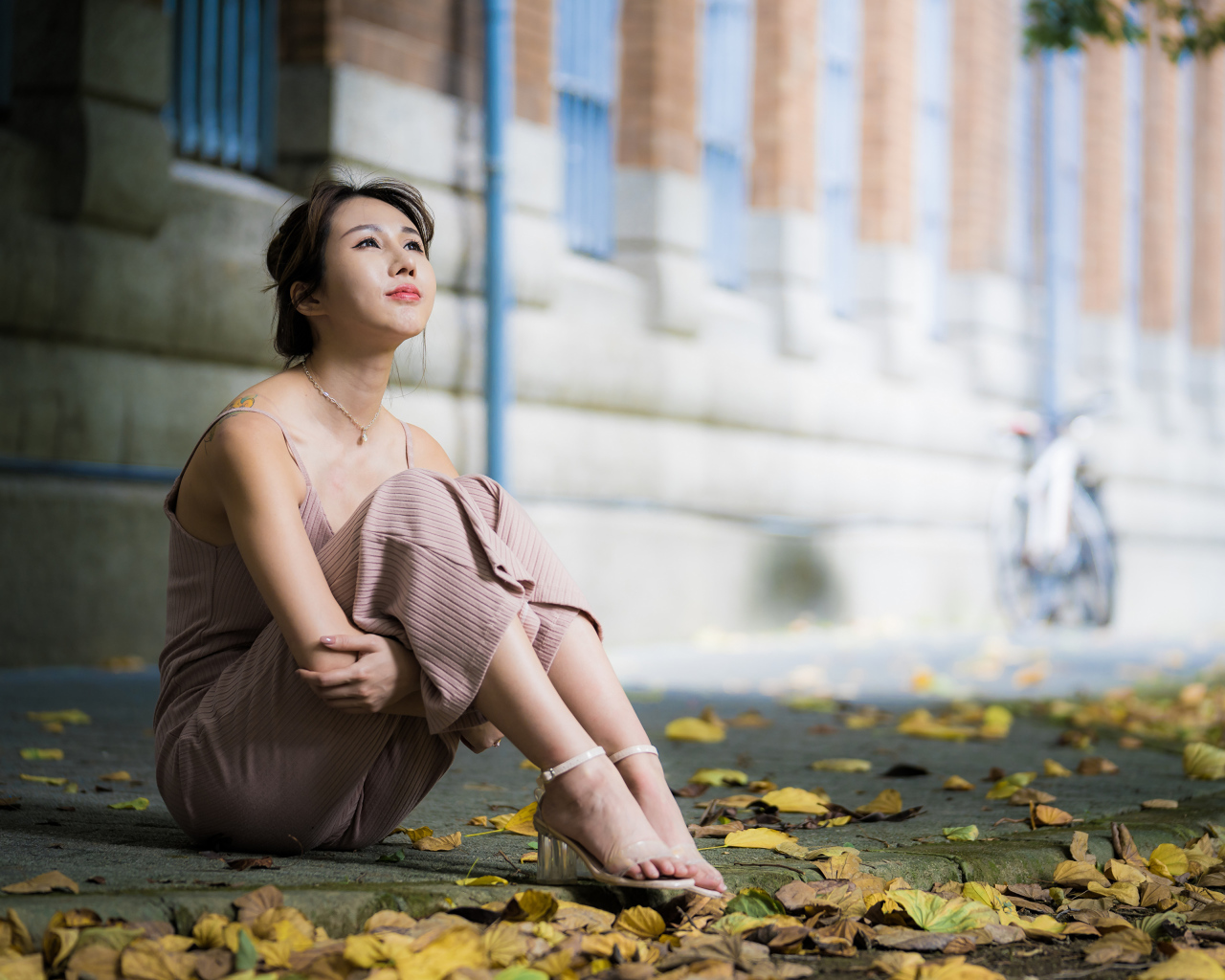 Молодая девушка азиатка сидит на земле с листьями 