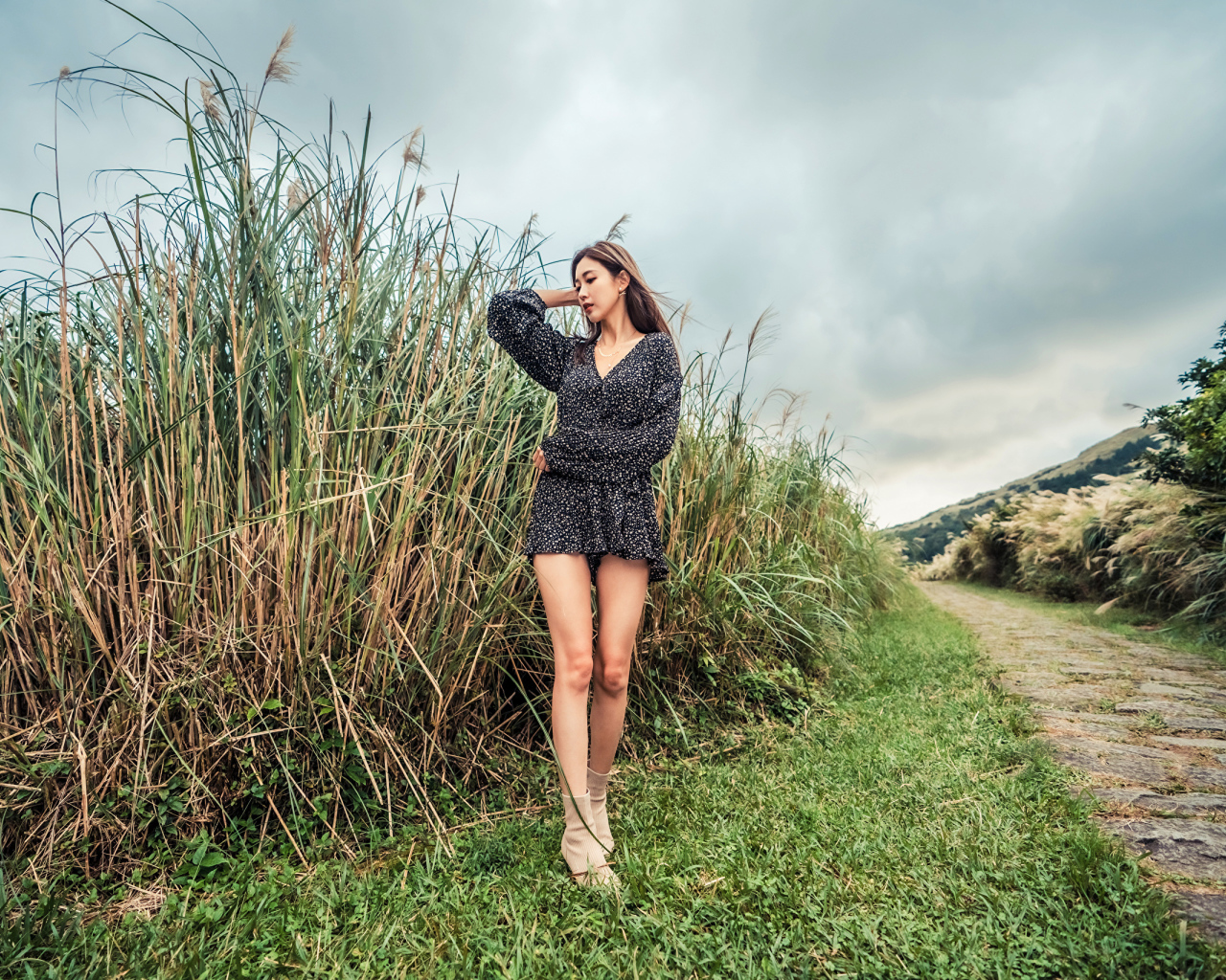 Молодая девушка азиатка стоит у зеленой травы