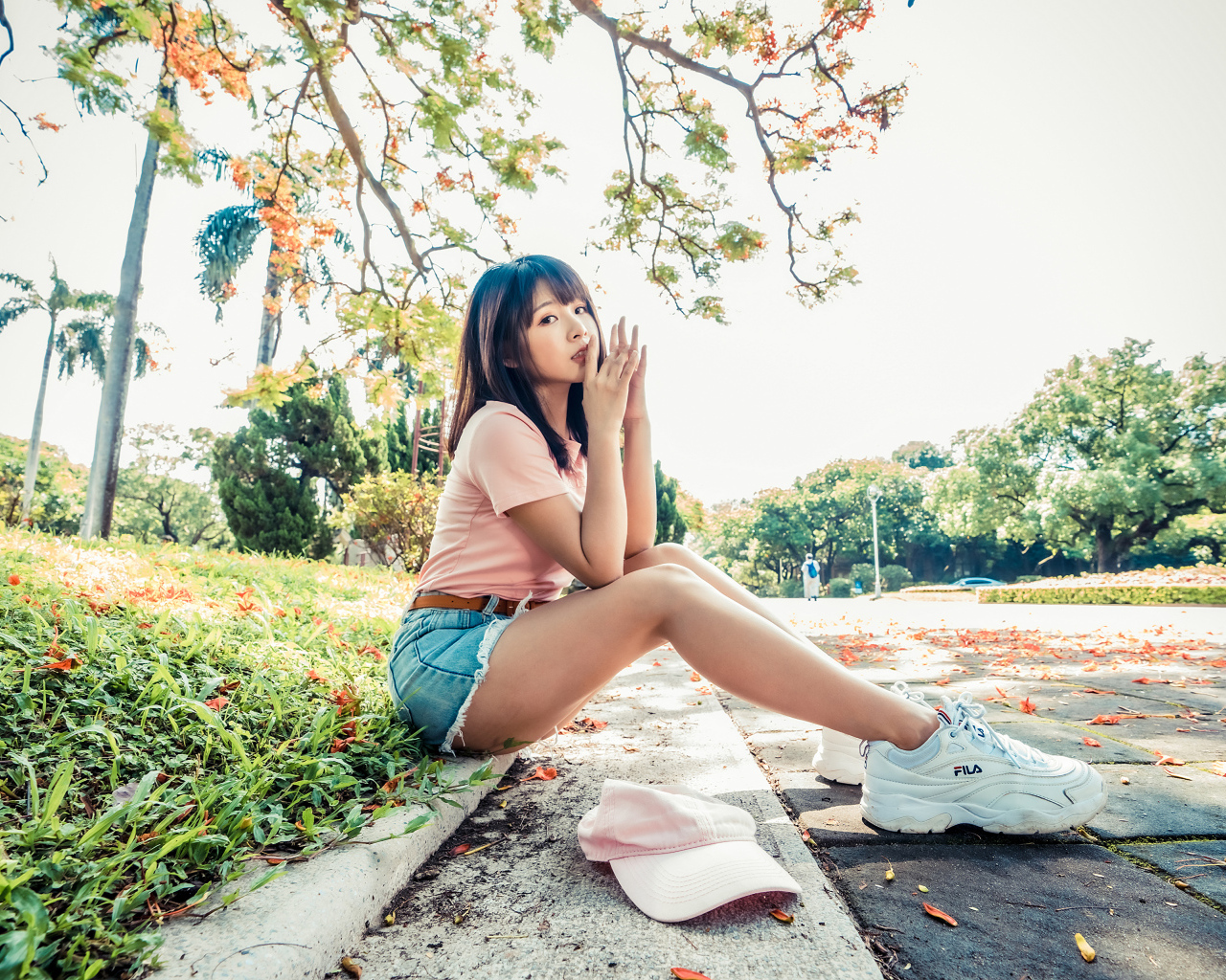 Молодая азиатка сидит на земле в осеннем парке