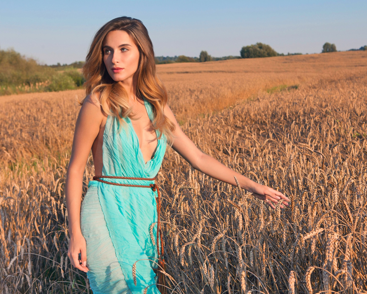 Молодая девушка в голубом платье на поле с пшеницей 