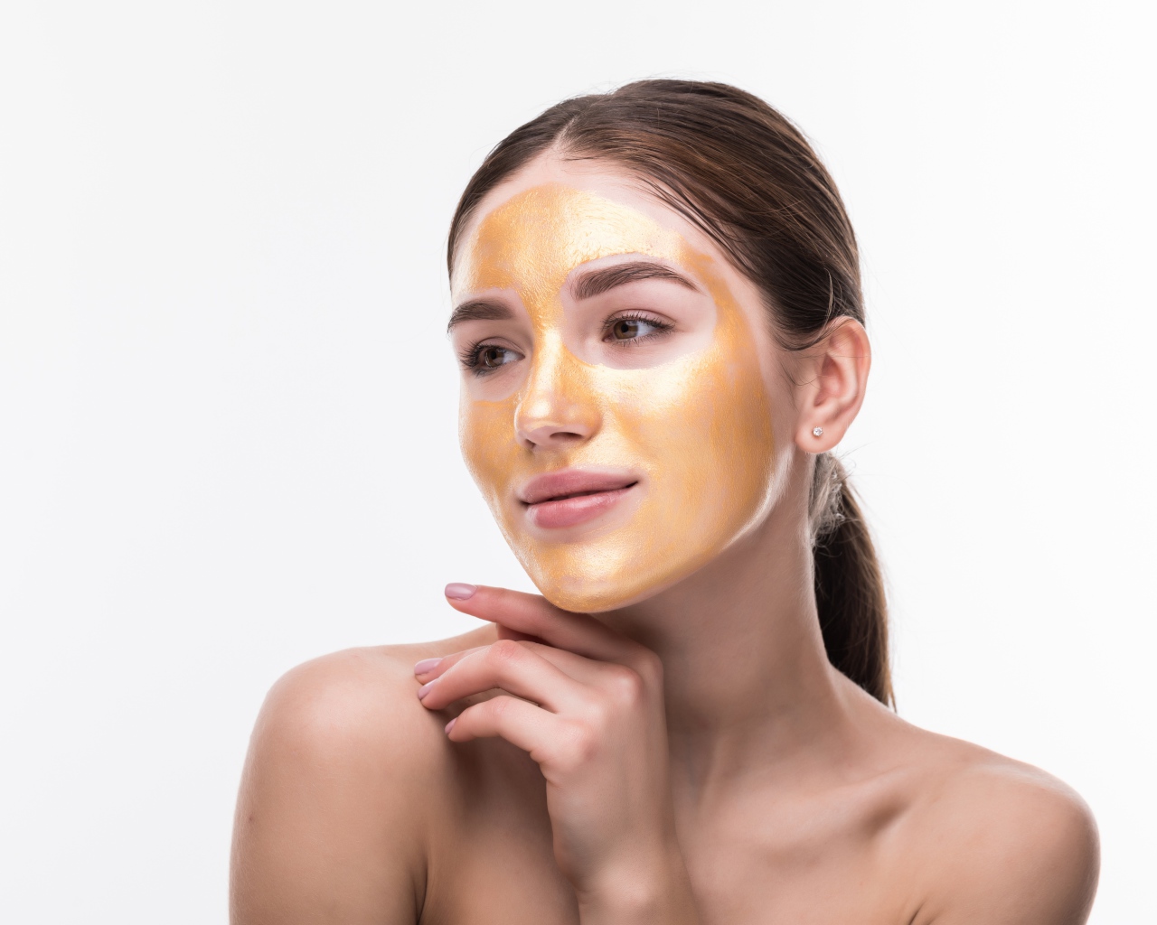 Молодая девушка без макияжа с золотой маской на лице