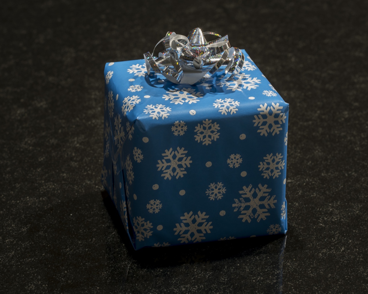 Большой голубой подарок с бантом на черном фоне 