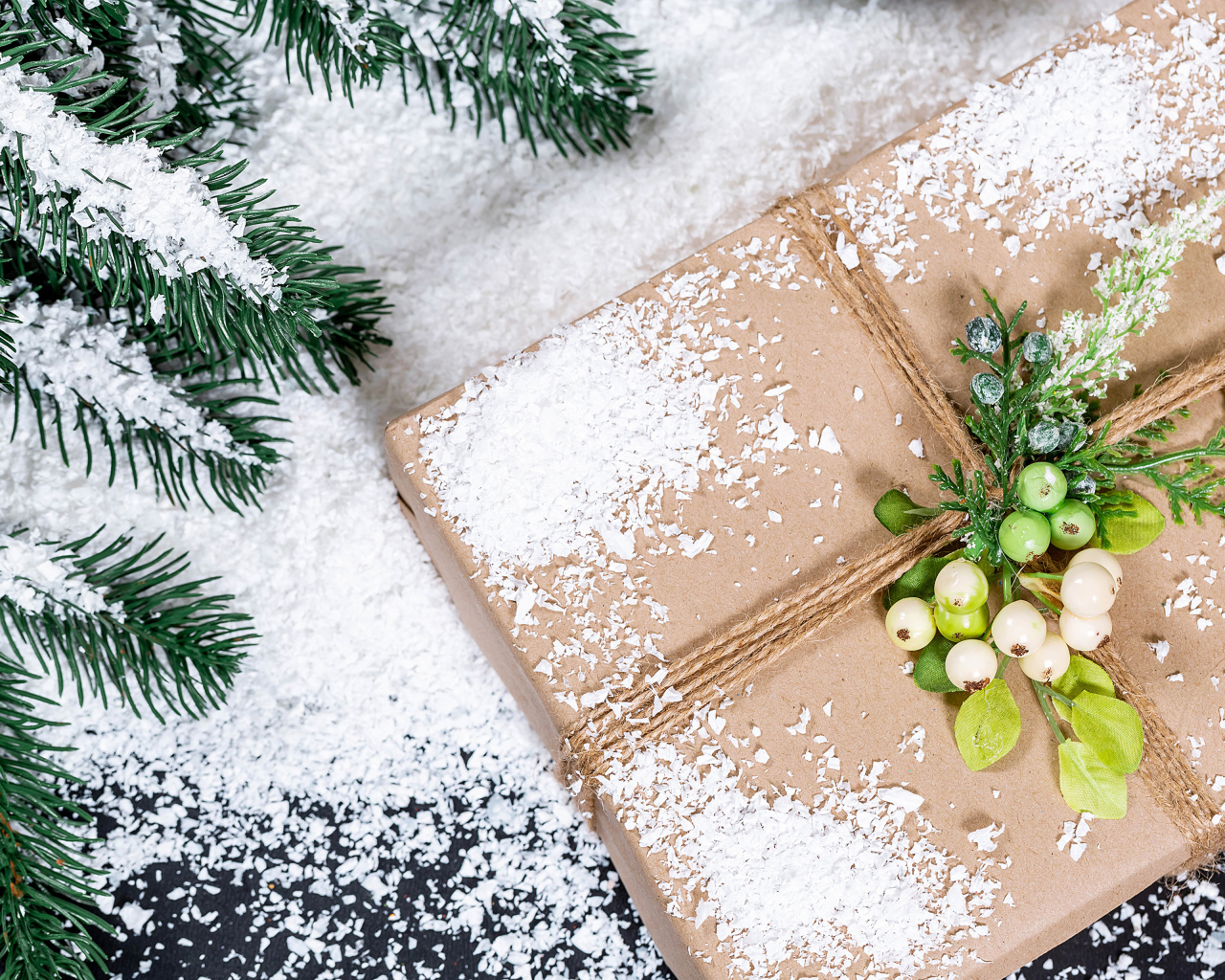 Подарок с заснеженной веткой ели на столе