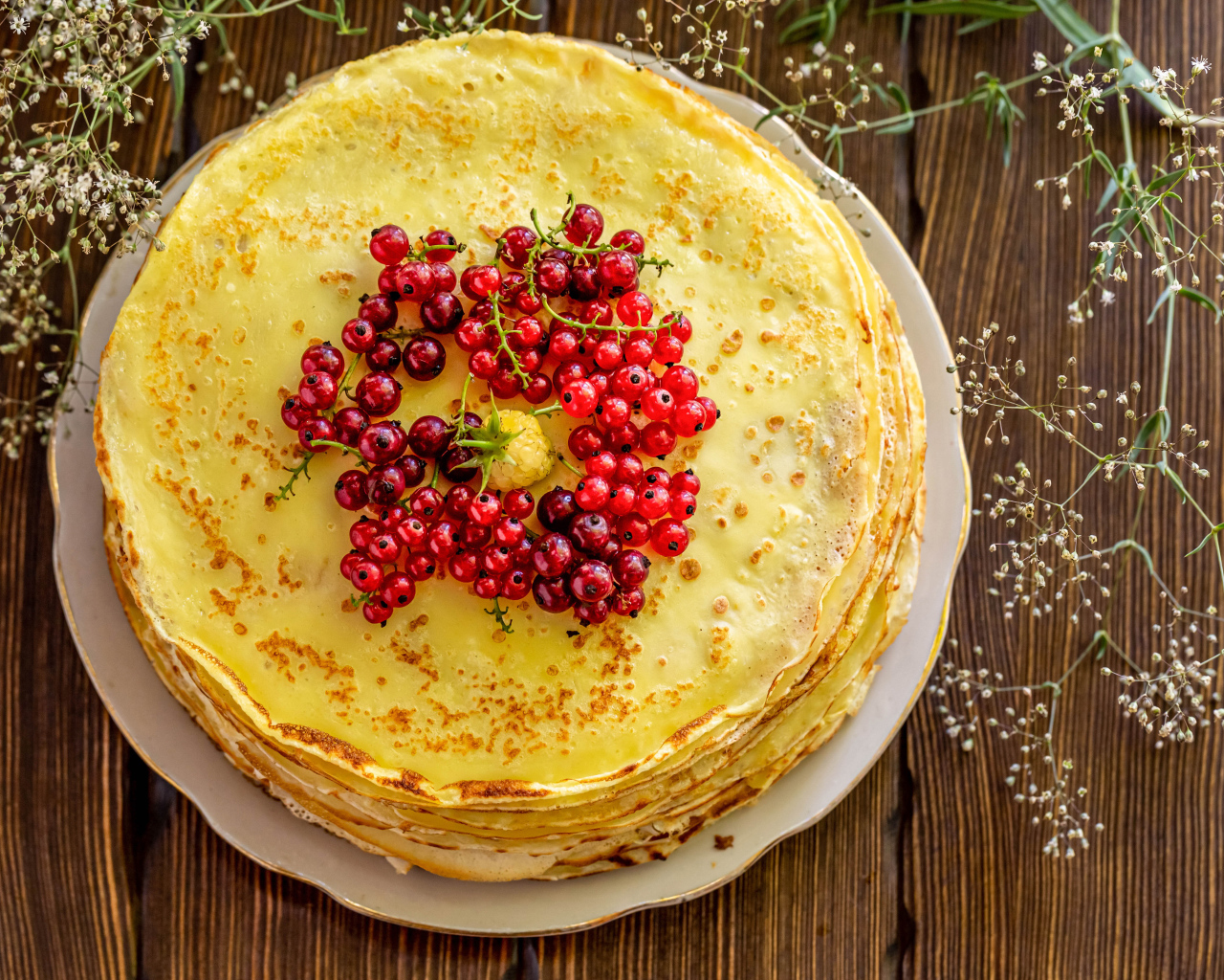 Аппетитные блины с ягодами красной смородины на столе 
