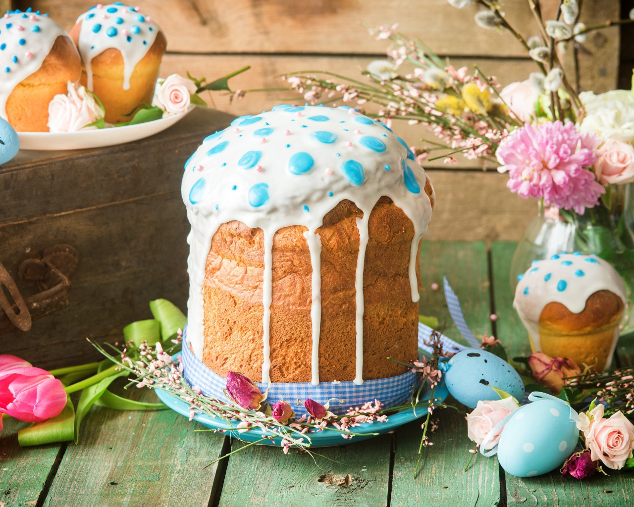 Красивый пасхальный кулич с белой глазурью на столе с цветами