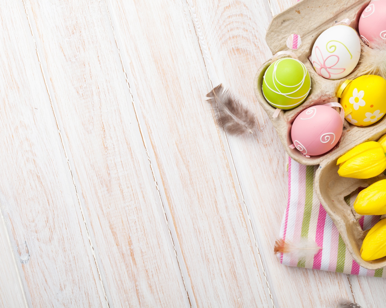 Крашеные пасхальные яйца на столе с тюльпанами