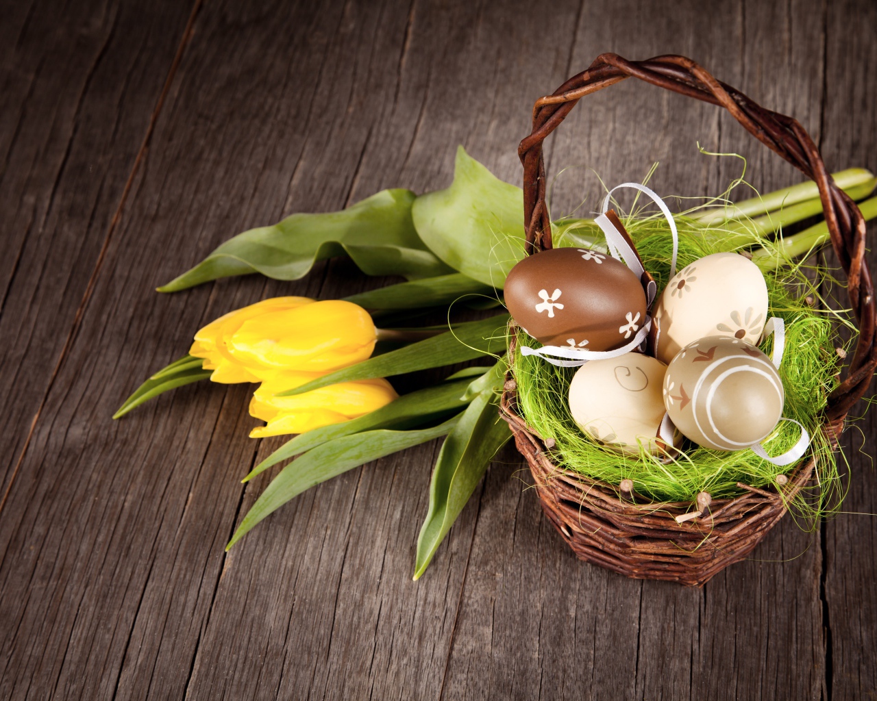 Маленькая корзина с пасхальными  яйцами на столе с тюльпанами