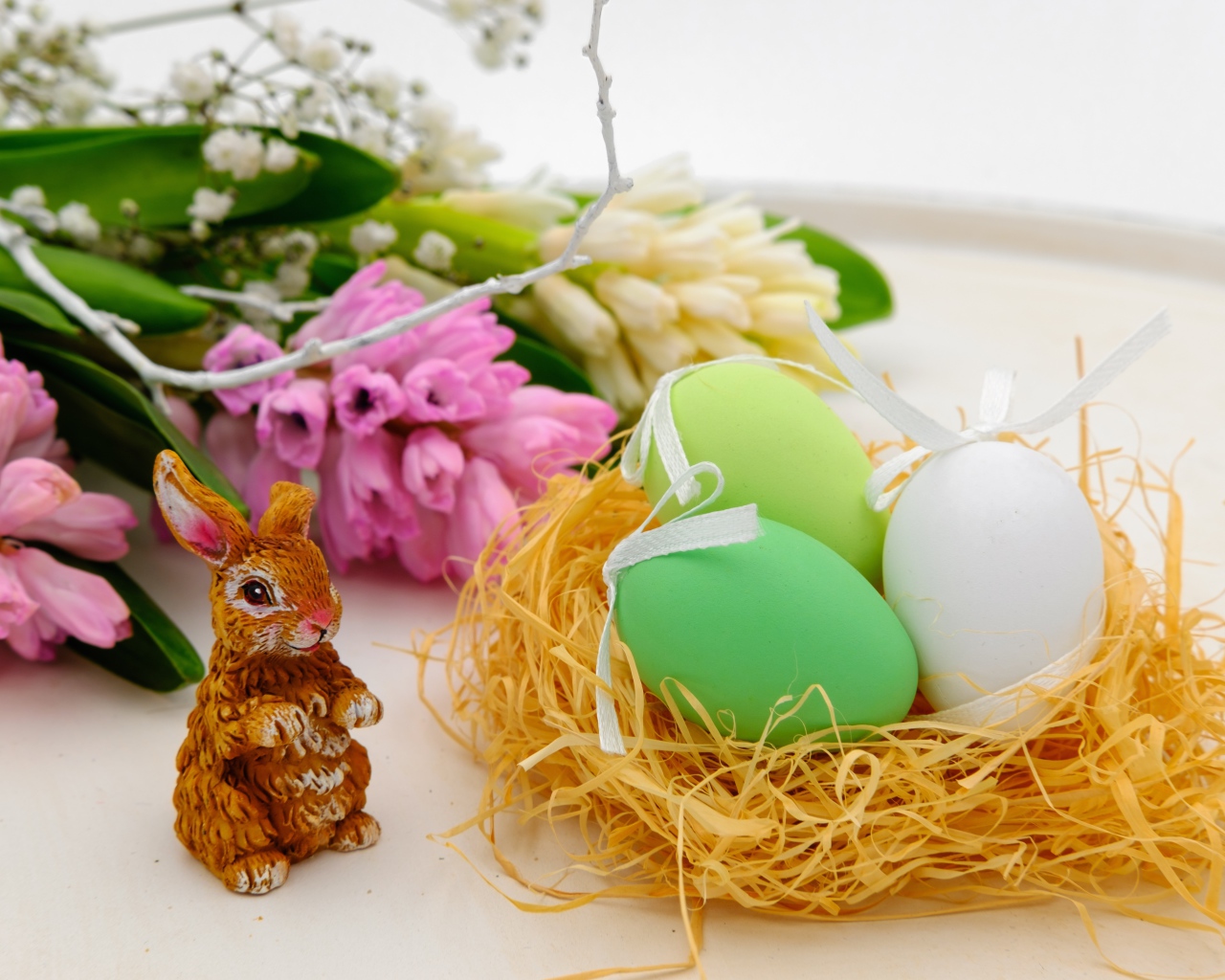 Три пасхальных яйца в гнезде на столе с цветами