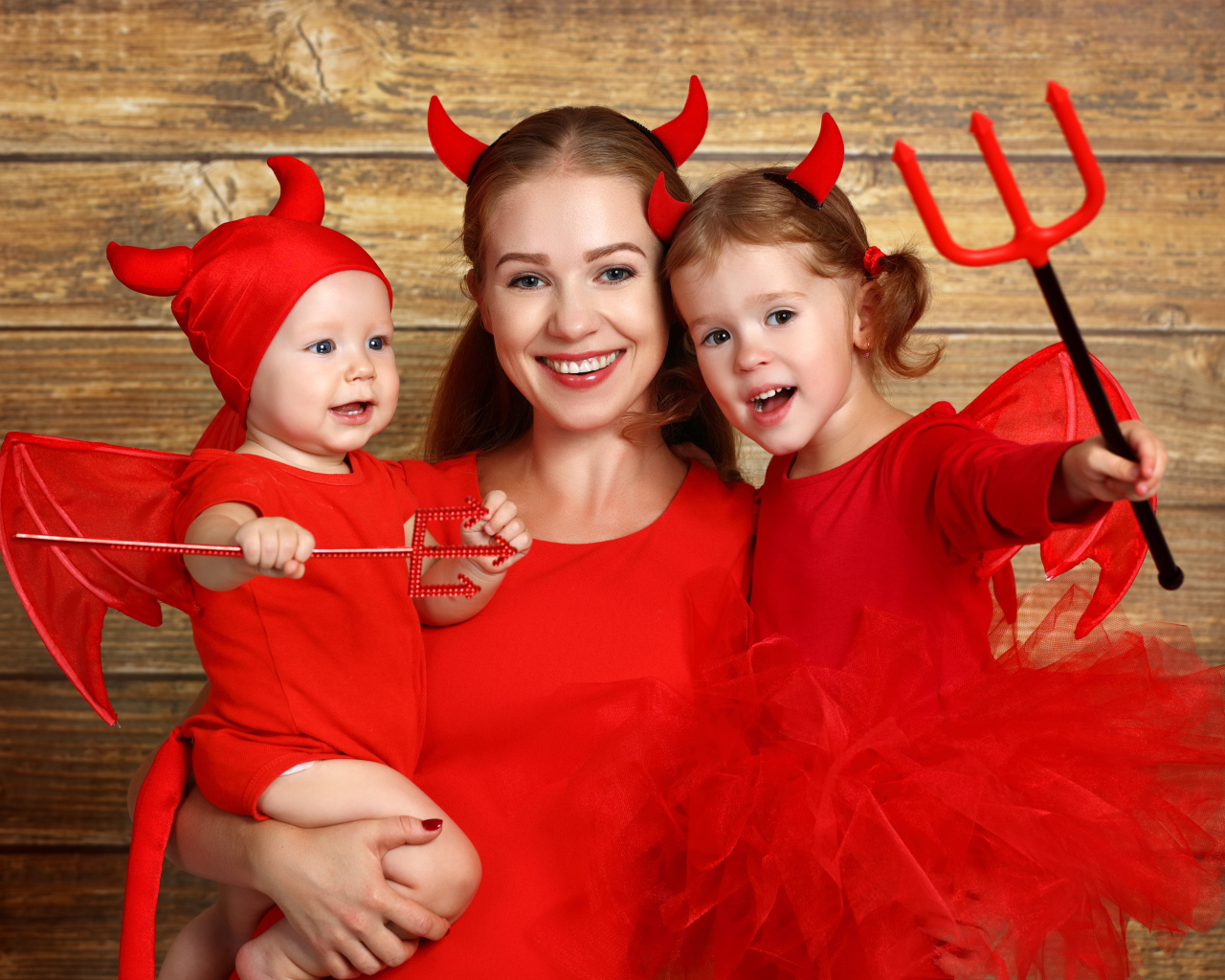 Женщина с двумя детьми в красных костюмах на Хэллоуин