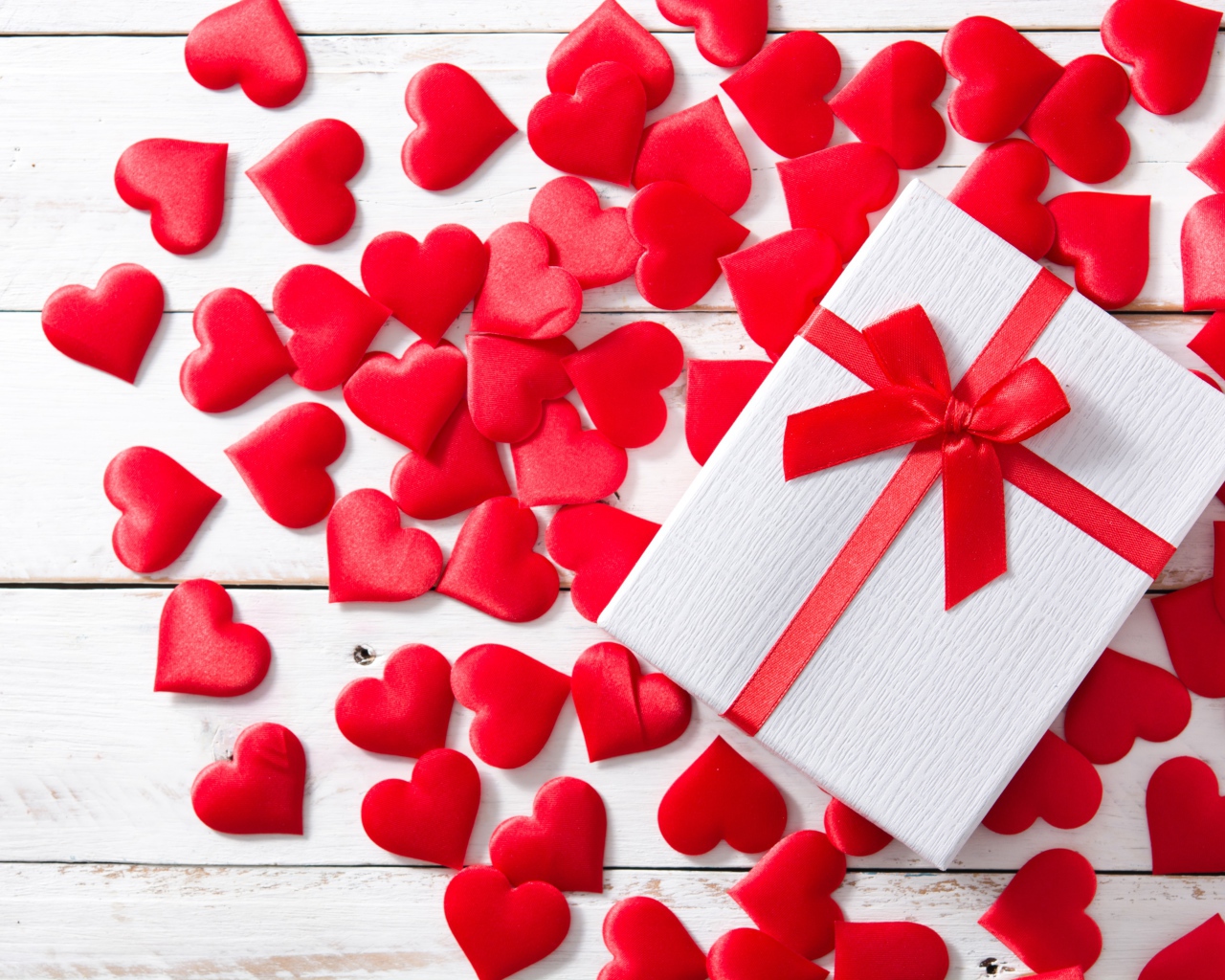 Подарок и много красных сердечек на белом фоне на День Святого Валентина
