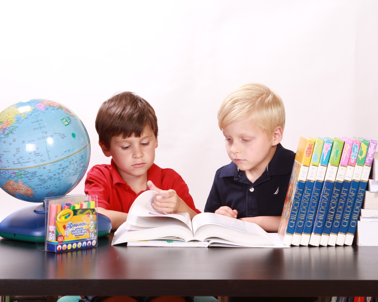 Два мальчика школьника с книгами и глобусом за столом