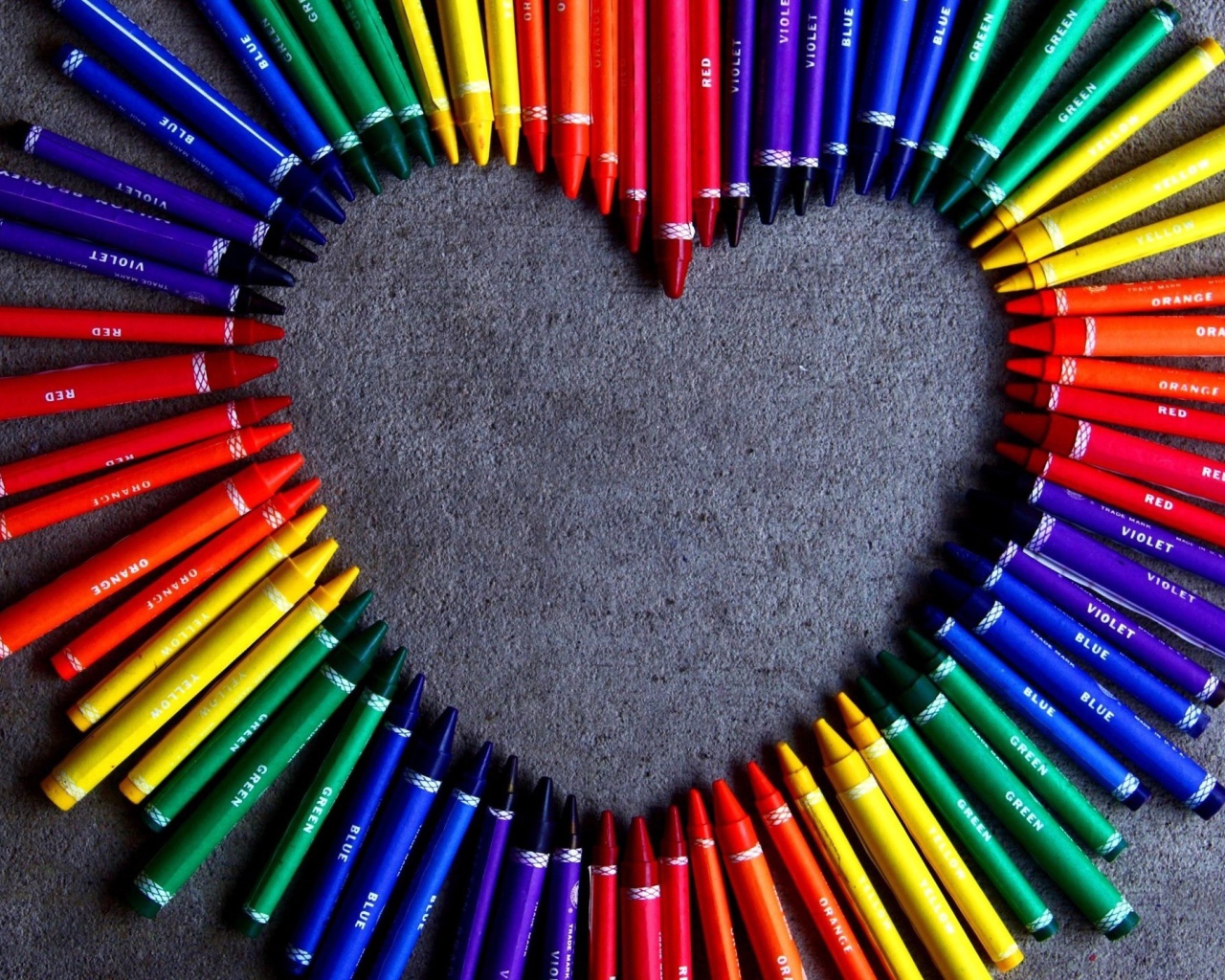 Heart made of multi-colored pencil on gray background