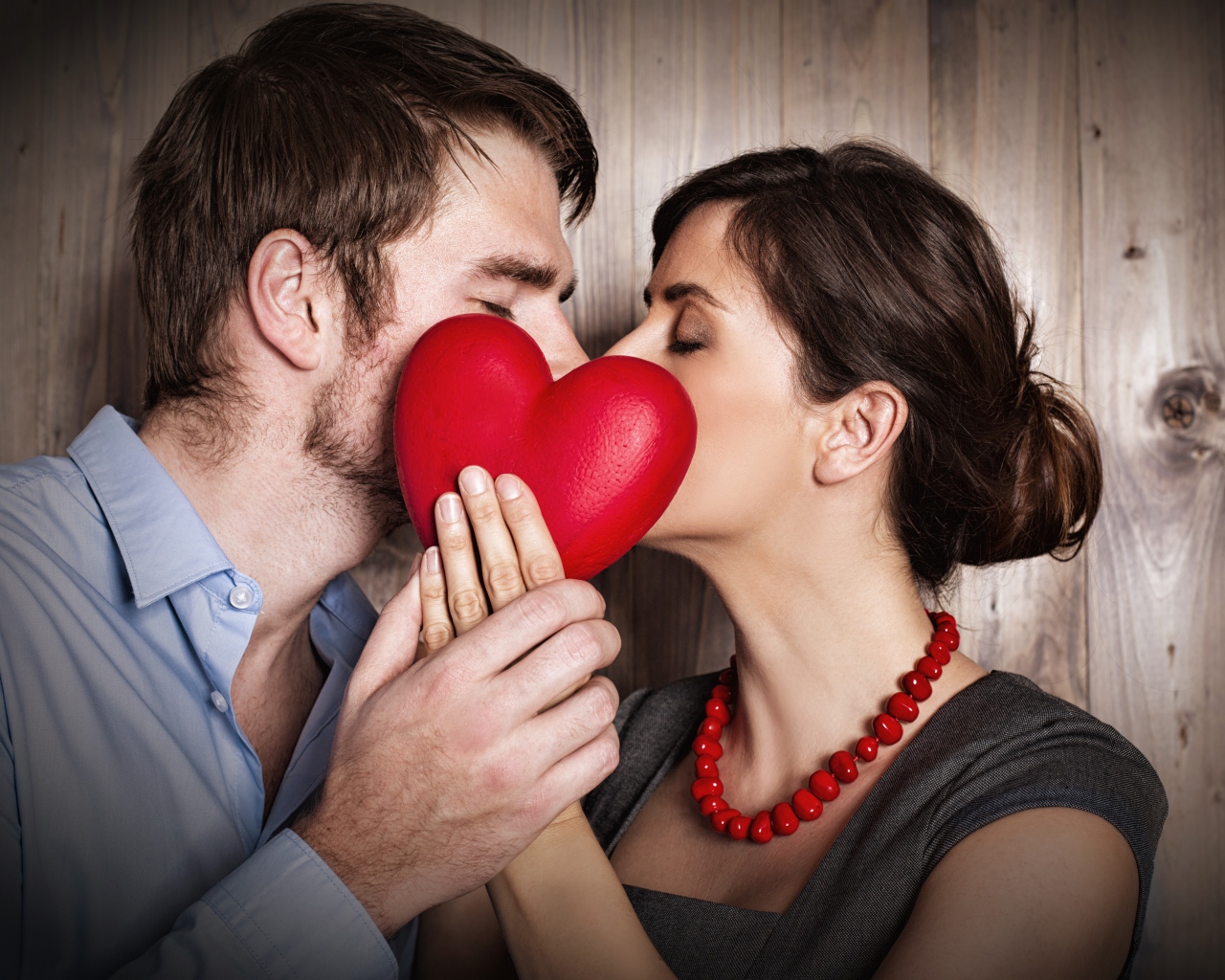 Поцелуй влюбленной пары за красным сердцем