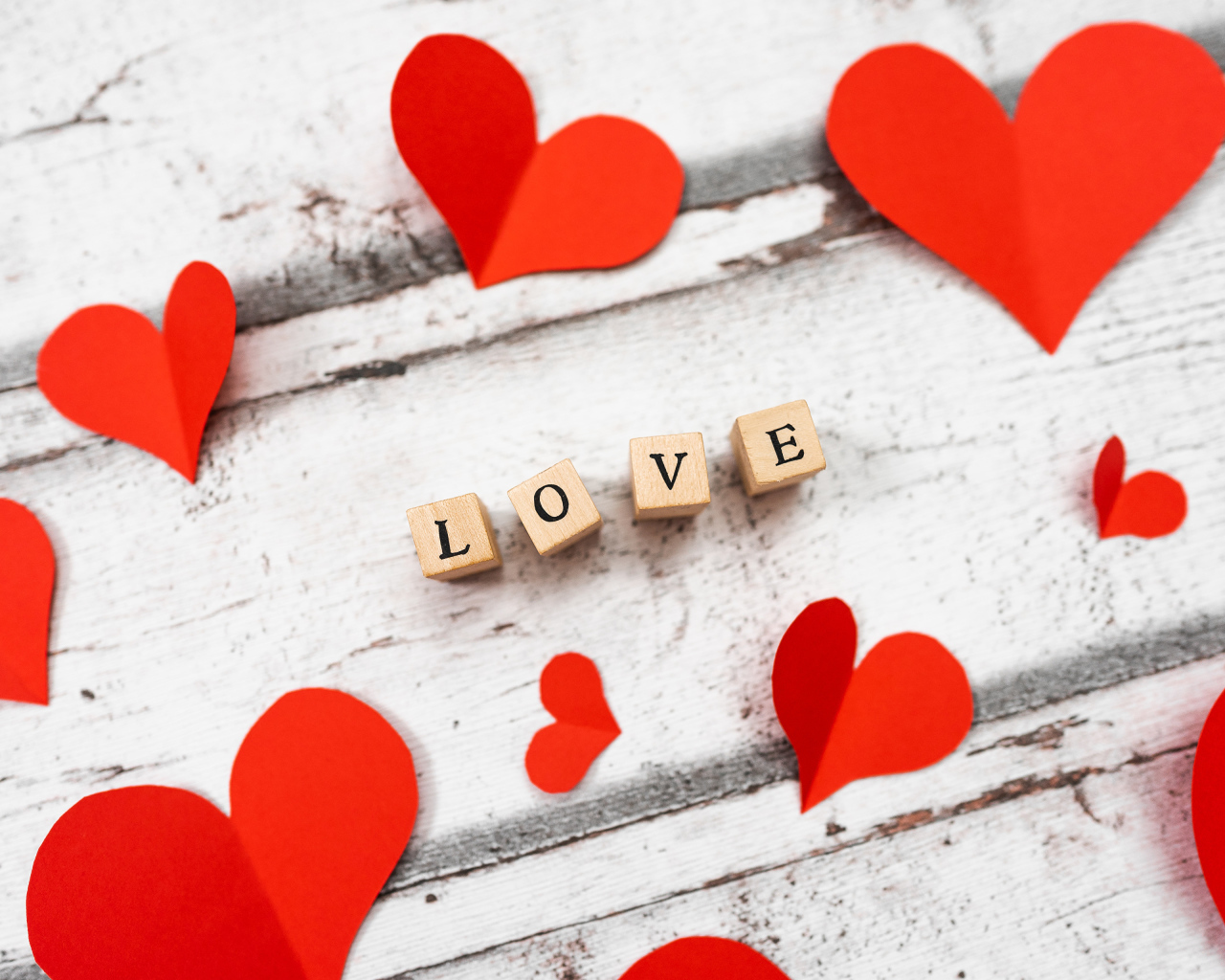 Красные сердечки и надпись любовь на деревянном столе 