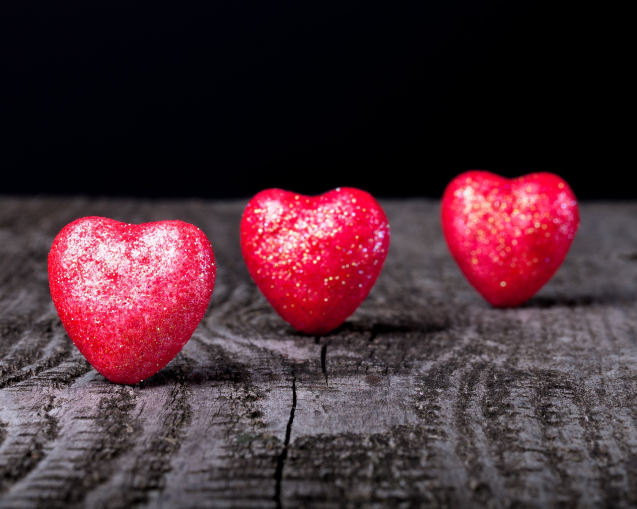 Блестящие красные сердечки на деревянном столе