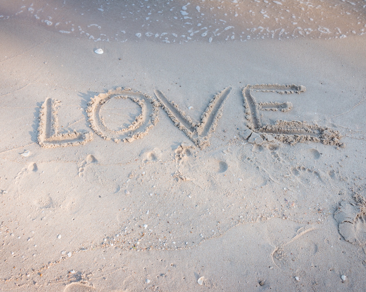 Надпись Любовь на мокром песке у моря