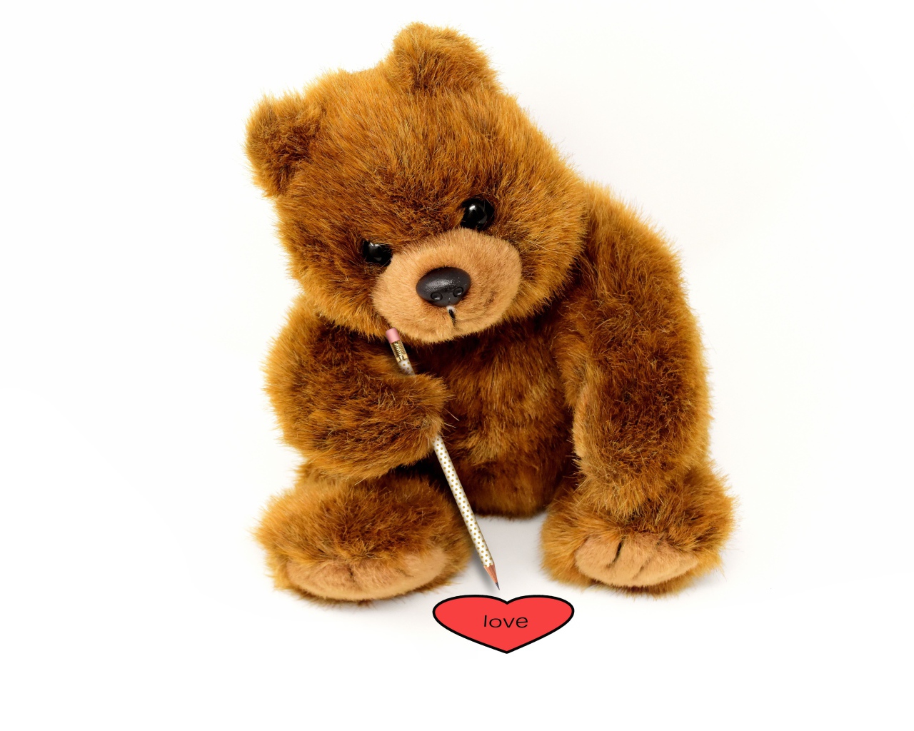 Игрушка медвежонок рисует сердце на белом фоне 