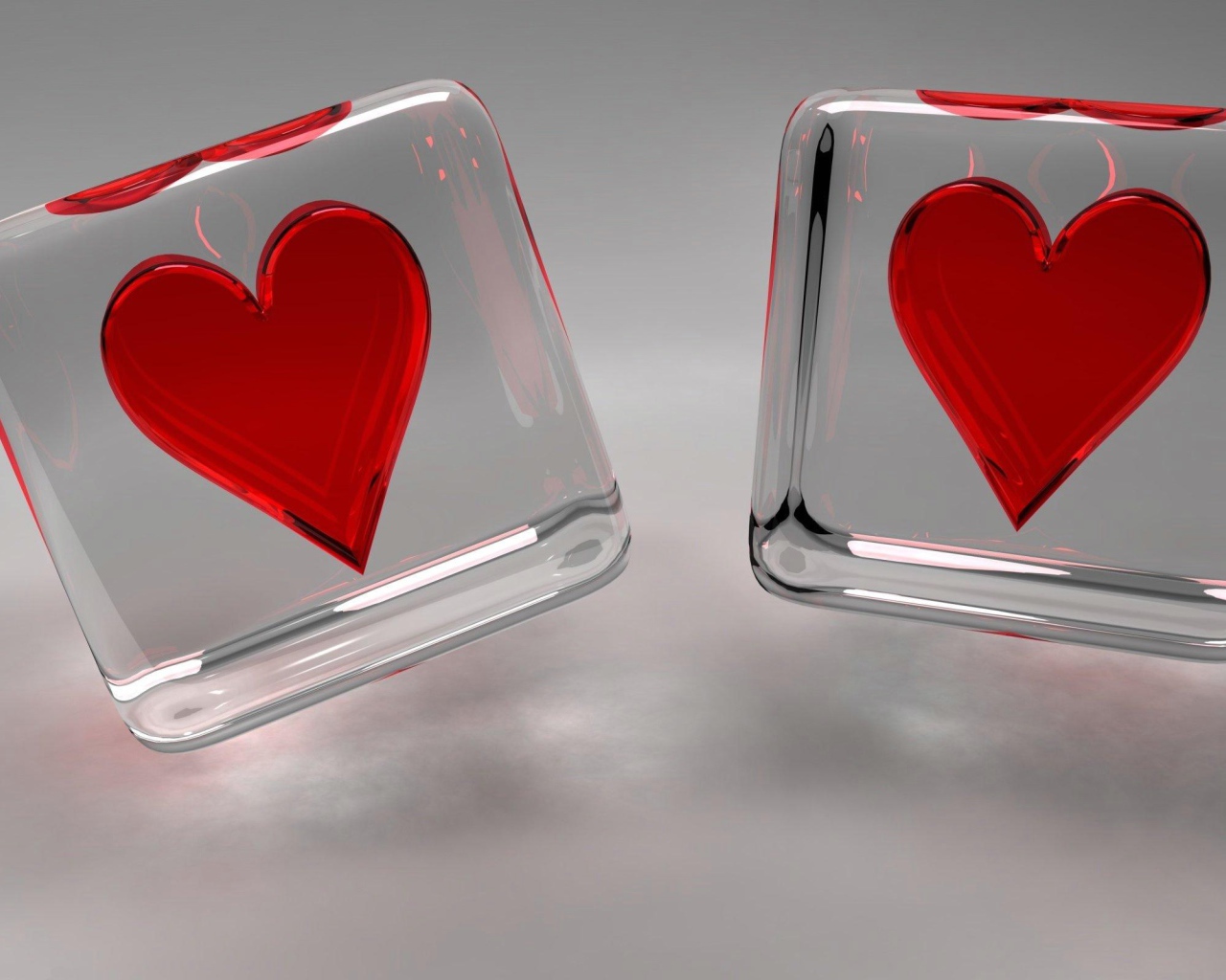 Два стеклянных кубика с сердечками на сером фоне